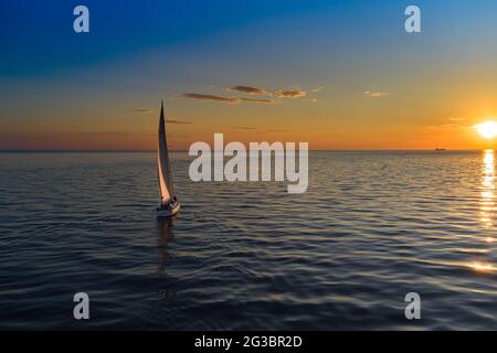 Riga, Lettland 12-06-2021 Segelyacht gegen Sonnenuntergang. Urlaub Lifestyle Landschaft mit Skyline Segelboot. Yachting Tourismus - maritimer Abendspaziergang. Rom Stockfoto