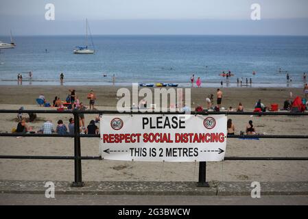 Ein Schild ‘Please respect Social Distancing“ im Fischerdorf Looe im Süden von Cornwall. Da die Coronavirus-Pandemie weiter anhält und mehr Menschen wählen Stockfoto