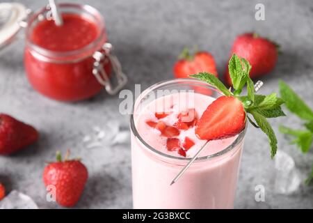 Aurvedische indische Erdbeere Lassi oder Milchshake auf grauem Hintergrund. Nahaufnahme. Traditionelles gesundes Getränk mit Erdbeeren, Joghurt, Früchten und Eiswürfel. Stockfoto