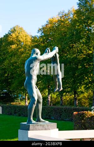 Die szenische Bronzeskulptur des Vaters, der mit seinem kleinen Sohn von Gustav Vigeland spielt, befindet sich auf der Brücke der Skulpturen, Frogner Park, Oslo, Norwegen Stockfoto