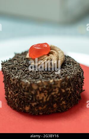 Cupcake mit Schokoriegel und Sahnehahne mit Kirsche Stockfoto