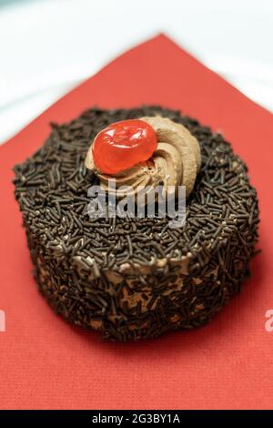 Cupcake mit Schokoriegel und Sahnehahne mit Kirsche Stockfoto