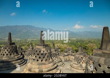 Der buddhistische Tempel Borobudur, der größte der Welt, mit seinen charakteristischen glockenförmigen Stupas, umgeben von den Bergen Indonesiens Stockfoto