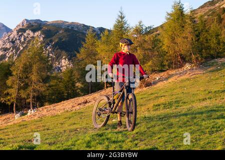 Frau, die an einem schönen Tag mit dem Mountainbike in der Natur bergauf geht. Stockfoto