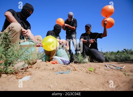 Gaza, Palästina. Juni 2021. Maskierte Palästinenser bereiten Brandballons vor, um vom Gazastreifen aus in Richtung Israel zu starten. Palästinensische Aktivisten starten brennende Ballons aus dem Gazastreifen in Richtung Israel, um gegen den derzeit stattfindenden flaggenmarsch in Ostjerusalem zu protestieren und um einen erneuten Ausbruch von Gewalt zu sorgen, da etwa 5,000 rechte Nationalisten mit der blau-weißen Flagge Israels durch die Jerusalemer Altstadt ziehen werden. Gaza-Brandballons verbrannten Ackerland an mindestens 13 verschiedenen Orten, berichtet israelische Medien. Kredit: SOPA Images Limited/Alamy Live Nachrichten Stockfoto