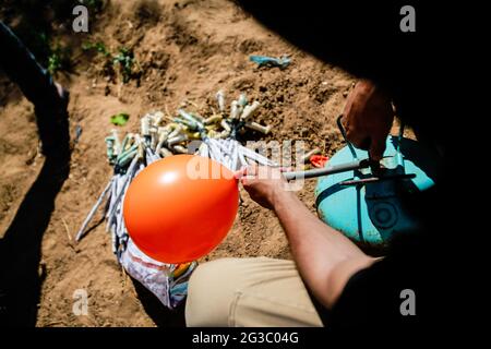 Gaza, Palästina. Juni 2021. Maskierte Palästinenser bereiten Brandballons vor, um vom Gazastreifen aus in Richtung Israel zu starten. Palästinensische Aktivisten starten brennende Ballons aus dem Gazastreifen in Richtung Israel, um gegen den derzeit stattfindenden flaggenmarsch in Ostjerusalem zu protestieren und um einen erneuten Ausbruch von Gewalt zu sorgen, da etwa 5,000 rechte Nationalisten mit der blau-weißen Flagge Israels durch die Jerusalemer Altstadt ziehen werden. Gaza-Brandballons verbrannten Ackerland an mindestens 13 verschiedenen Orten, berichtet israelische Medien. Kredit: SOPA Images Limited/Alamy Live Nachrichten Stockfoto