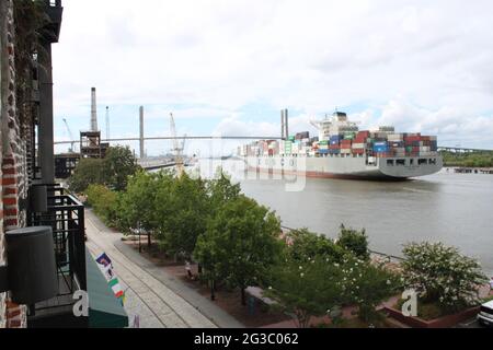 Containerschiff nähert sich der Hängebrücke über den Fluss, wie von der Promenade in Savannah Georgia aus gesehen Stockfoto