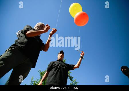 Maskierte Palästinenser bereiten Brandballons vor, um vom Gazastreifen aus in Richtung Israel zu starten. Palästinensische Aktivisten starten brennende Ballons aus dem Gazastreifen in Richtung Israel, um gegen den derzeit stattfindenden flaggenmarsch in Ostjerusalem zu protestieren und um einen erneuten Ausbruch von Gewalt zu sorgen, da etwa 5,000 rechte Nationalisten mit der blau-weißen Flagge Israels durch die Jerusalemer Altstadt ziehen werden. Gaza-Brandballons verbrannten Ackerland an mindestens 13 verschiedenen Orten, berichtet israelische Medien. (Foto von Ahmed Zakot/SOPA Images/Sipa USA) Stockfoto