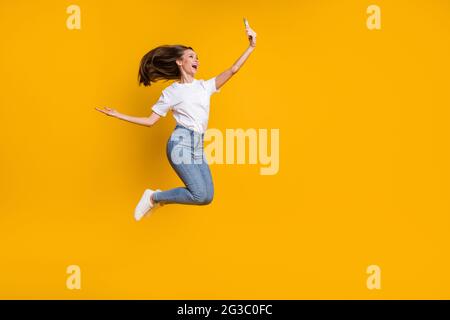 In voller Länge Körpergröße Foto von Frau, die Selfie werfen Haare springen lächelnd isoliert auf hellgelben Hintergrund mit Copyspace Stockfoto