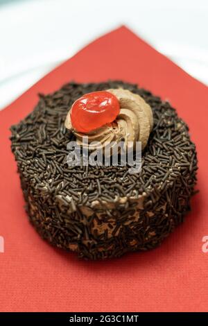 Cupcake mit Schokoriegel und Sahnehahne mit Kirsche Stockfoto