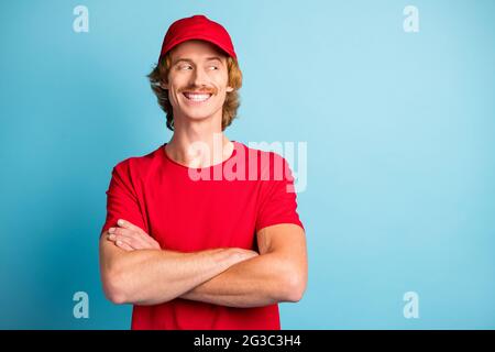 Portrait der fröhlichen Person gefalteten Armen schauen interessiert leeren Raum toothy Lächeln isoliert auf blauem Hintergrund Stockfoto