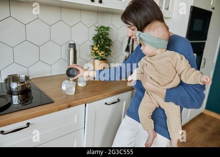 Mutter gießt Wasser in die Flasche, um Milch vorzubereiten Stockfoto