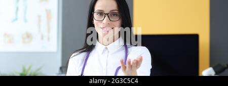 Ärztin mit Stethoskop sitzt am Tisch im Büro Stockfoto