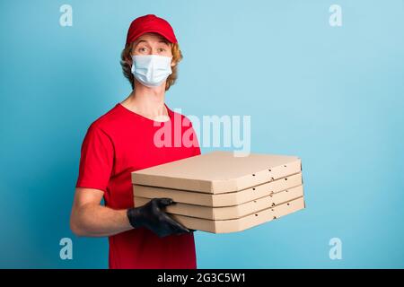 Porträt von halb gedreht gutaussehend Kerl halten Pizzen tragen medizinische Gesundheitsversorgung Atemwege isoliert auf blauem Hintergrund Stockfoto