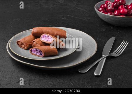 Dünne Schokoladenpfannkuchen gefüllt mit Quark, Heidelbeere und Kirsche Stockfoto