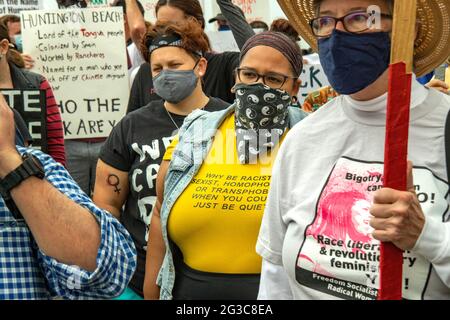 Eine Frau, die in Huntington Beach, CA, demonstriert, die sich gegen die Coronavirus-Pandemie maskiert hat, drückt ihre Meinung zu anderen Demonstranten mit einem Schild auf ihm aus Stockfoto