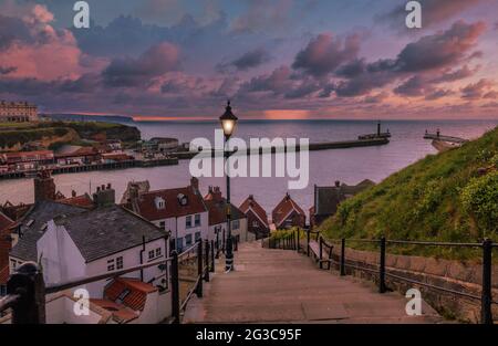 Der Blick von den berühmten 199 Stufen auf den Hafen von Whitby. Wird bei Sonnenuntergang aufgenommen und erzeugt einen schönen rosa Glanz. Stockfoto