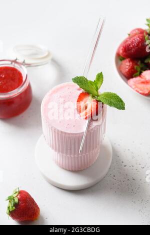 Erdbeerlassi, Smoothie oder Milchshake auf weißem Hintergrund. Vertikales Format. Nahaufnahme. Gesunde Milchprodukte indisches Getränk. Nicht-alkoholische Kinderdess Stockfoto