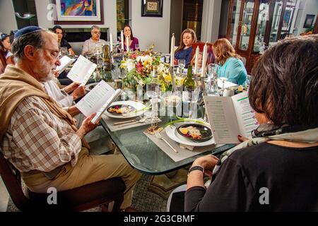 Am traditionellen Esstisch für ein Passahseder in einem jüdischen Haus in Südkalifornien lasen die Gäste die Haggadah, einen jüdischen Text, der die darlegt Stockfoto