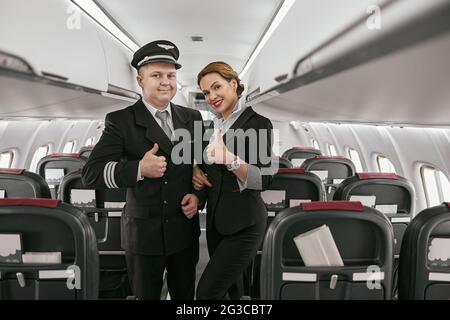 Pilot und Stewardess zeigen den Daumen im Flugzeug Stockfoto