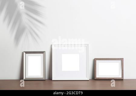 Hintergrund mit leerem weißen Rahmen nachahmen. Verschiedene dekorative leere Rahmen für ein Foto oder Gemälde in einem hellen skandinavischen minimalistischen Interieur auf einer weißen sauberen Wand. Hochwertige Fotos Stockfoto