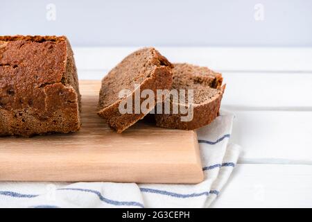 Sauerteig Roggenbrot auf einem Schneidebrett auf weißem Holztisch mit Kopierplatz geschnitten Stockfoto
