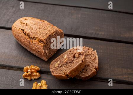 Scheiben Nussbaumsauerteig Brot auf dunklem Holzhintergrund mit Kopierraum Stockfoto