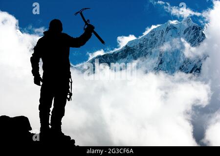 Silhouette des Menschen mit Eispickel in der Hand und in den Bergen Mit Wolken - Mount Thamserku und Mount Kangtega - Nepal Stockfoto