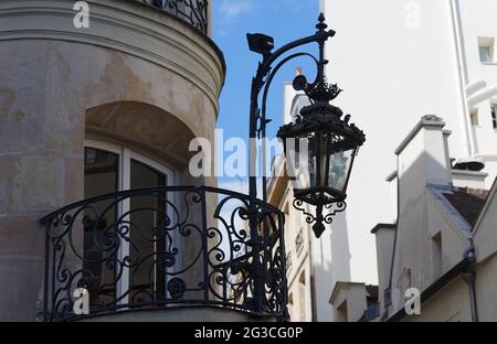 Typische und alte Metall-Straßenlampe, die auf dem Gebäude aufgehängt ist. Laterne, die an der Hauswand hängt. Paris Stockfoto