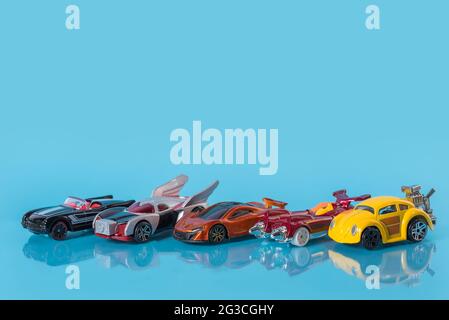 Viele bunte Spielzeugautos auf blauem Hintergrund, kleine Automodelle Stockfoto