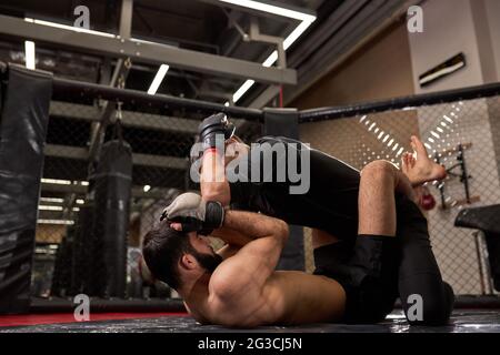 Seitenansicht der Kämpfer der MMA Boxer kämpfen im Käfigring im Fitnessstudio ohne Regeln. MMA Kämpfer im Ring Vorbereitung für die Meisterschaft. Boxen Kämpfe mit Stockfoto