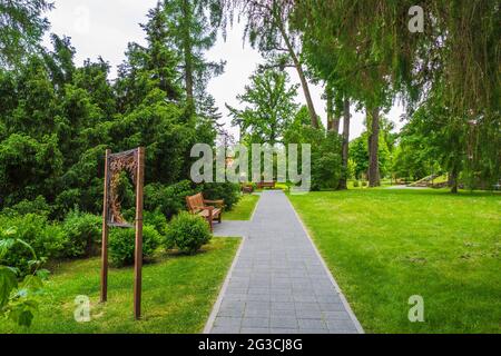 Stein gepflasterter Pfad mit grünen Rasen und Baum auf beiden Seiten im Park Stockfoto