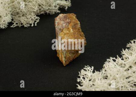 Andalusit aus Brasilien oder China. Natürlicher Mineralstein auf schwarzem Hintergrund, umgeben von Moos. Mineralogie, Geologie, Magie, Halbedelsteine und Stockfoto