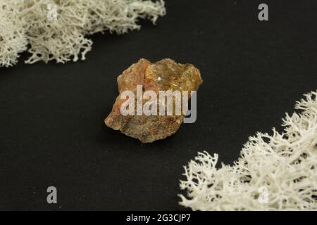 Andalusit aus Brasilien oder China. Natürlicher Mineralstein auf schwarzem Hintergrund, umgeben von Moos. Mineralogie, Geologie, Magie, Halbedelsteine und Stockfoto