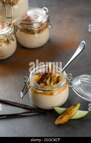 Apfel- und Zimtpudding in einem Glasgefäß auf dunklem Steingrund Stockfoto