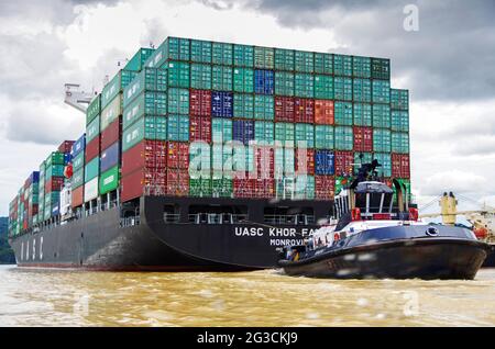 Riesiges panamax-Containerschiff im panamakanal, unterstützt von einem Schlepper Stockfoto