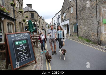 Die Menschen gehen die Straßen von Grassington in den Yorkshire Dales hinauf. Die Stadt wurde kürzlich genutzt, um die neue Serie der klassischen TV-Serie All zu Filmen Stockfoto