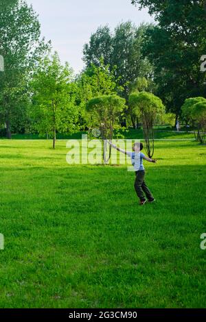 Ein Junge spielt Badminton während der Erholung im Freien, Rasen im Park Stockfoto