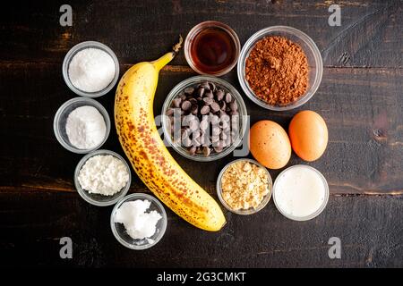 Erdnussbutter Chocolate Chip Muffins Zutaten: Schokoladenchips, Erdnussbutterpulver und andere Zutaten auf dunklem Holz Stockfoto
