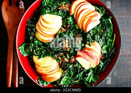 Kale Salat mit Äpfeln und Nüssen: Ein gesunder Salat aus toskanischem Grünkohl, honigsüßen Äpfeln, Pekannüssen und anderen Zutaten Stockfoto