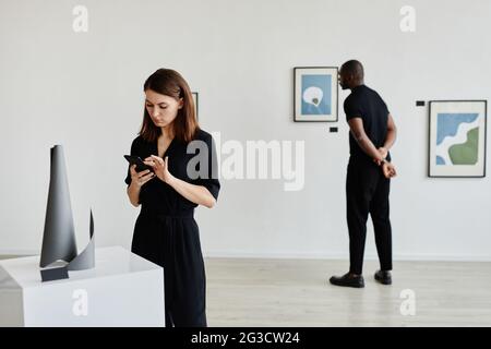 Minimalporträt eleganter junger Menschen, die abstrakte Gemälde und Skulpturen in der Galerie moderner Kunst betrachten, Kopierraum Stockfoto