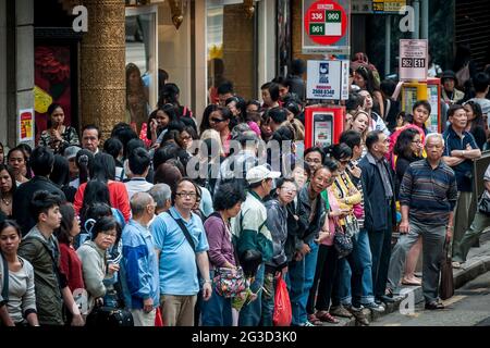 Auf der des Voeux Road, Central, Hong Kong Island, warten Pendler zur Hauptverkehrszeit auf Busse Stockfoto