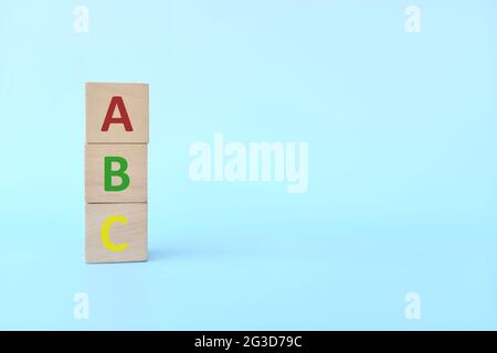 Bunte ABC-Buchstaben auf Holzblöcken auf blauem Hintergrund mit Kopierraum. Beginn des Kindes oder des Kindes, das Alphabet-Konzept zu erlernen. Stockfoto