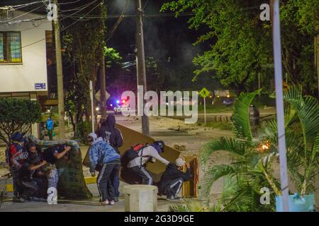 Demonstranten der Frontline vor Tränengaskanistern und Stuntgranaten hinter einer Matratze, als Demonstranten und die kolumbianische Bereitschaftspolizei (ESMAD) in der Nacht des 14. Juni 2021 in Yumbo - Cali, Valle del Cauca - Kolumbien während regierungsnahe Proteste in der 7. Woche gegen die Regierung von Präsident Ivan Duque enthüllen, waren mindestens 70 Tote durch Unruhen und Gewalt zu Tode gekommen. Stockfoto