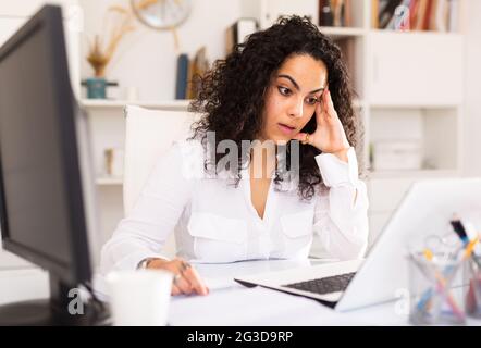 Frustrierte Frau, die allein im Büro arbeitet Stockfoto