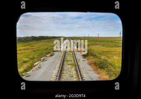 Russland - 02.09.013 - Blick vom Zugfenster auf die Schienen, die Steppe und den Himmel in Wolken. Stockfoto