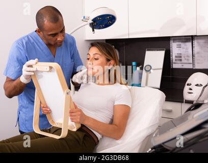 Männliche Kosmetikerin, die Frau vor der Gesichtsbehandlung konsultiert Stockfoto