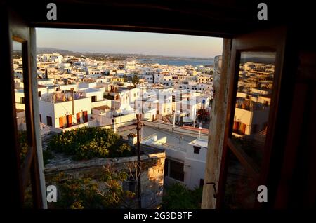 Ein Blick auf den Sonnenuntergang durch ein Fenster eines Ladens in Naxos, Griechenland Stockfoto