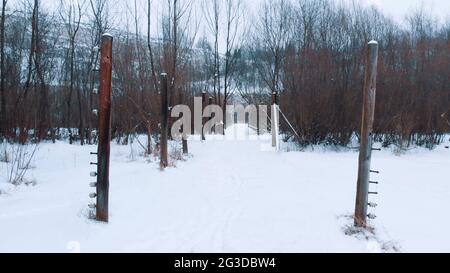 Vorderansicht der elektrischen Zaunmasten im Liban Kamieniolom. Der Ort, an dem der Film die Schindler´s-Liste gedreht wurde. Krakau, Polen. Baumhain im Hintergrund. Das ganze Gebiet ist mit Schnee bedeckt. Stockfoto