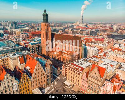 Breslau, Polen 02.15.2021 - Kirche der heiligen Maria Magdalena und Elisabeth. Panoramablick auf Gebäude in der Stadt. Rauch kommt aus Kaminen und berührt den klaren blauen Himmel im Hintergrund. Stockfoto